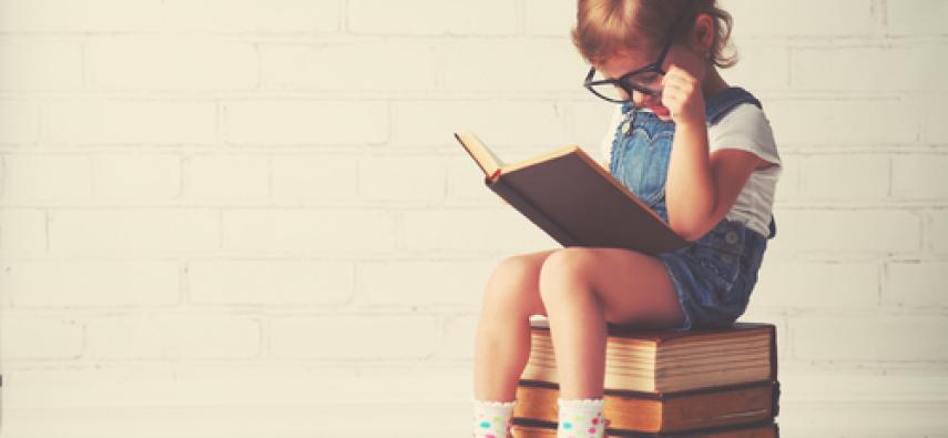 dziecko siedzące na książkach
